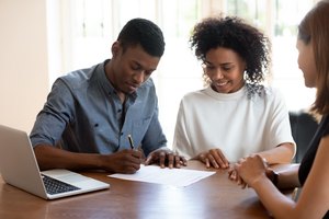 Happy young banking worker watching african ethnicity client signing agreement.