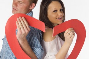 Couple holding two torn parts of a heart
