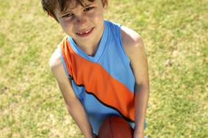 Young player holding football, looking up at coach