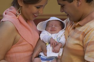 Close-up of a young couple holding their baby and smiling