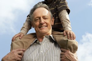 Boy (5-7 years) on grandfather's shoulders outdoors, smiling, portrait