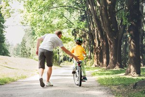 Father help his son ride a bicycle