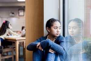 Angry middle school girl sits on library windowsill