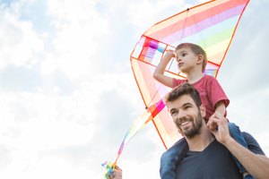 Little boy flying a kite with his father