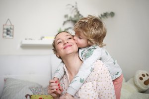 A little boy taking his mum in his arms in the bedroom